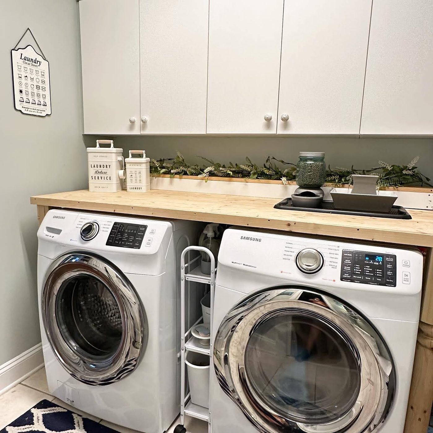 A calm laundry room with a wood counter over the washer and dryer and matching canisters